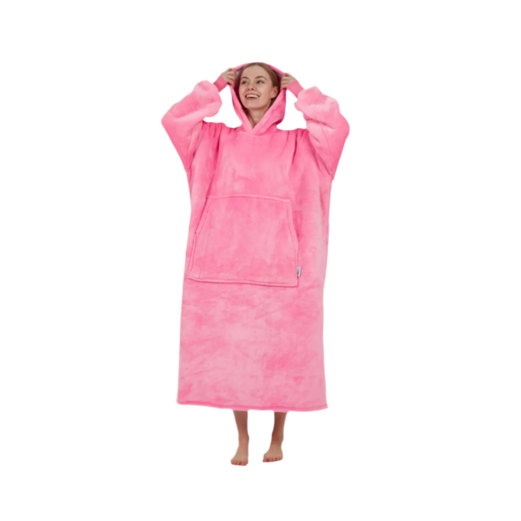 Woman lifting hood of oversized pink wearable blanket with relaxed pose.