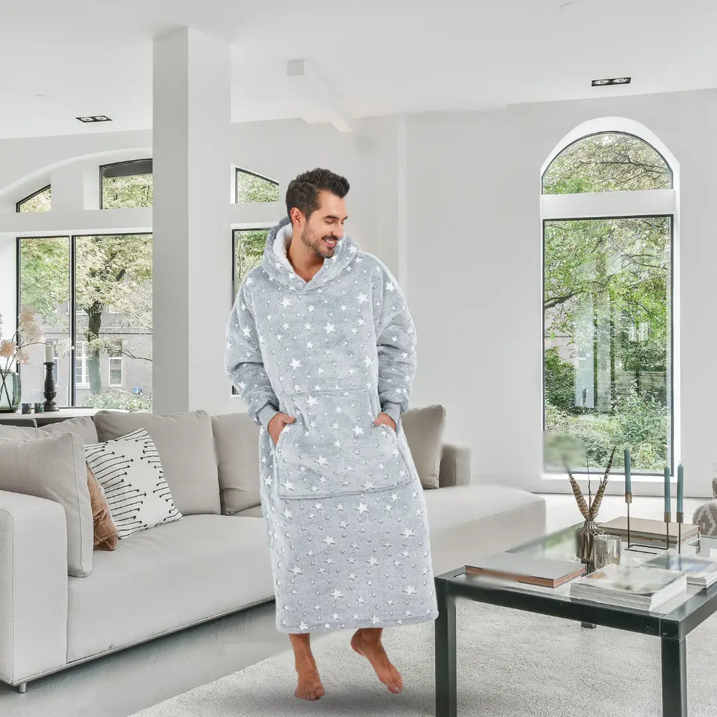 Man wearing Starry Elegance hoodie blanket standing in bright modern living room